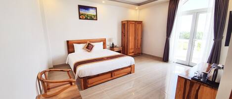 A hotel room with a bed, wooden furniture, a desk, and a large window.