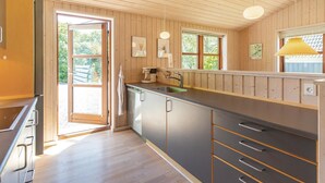 Eine moderne Küche mit Holzwänden, einem Edelstahlspülbecken und einem eingebauten Backofen.