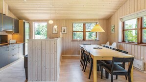Ein Holzinnenraum mit Küche, Essbereich und großen Fenstern.