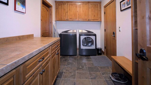 A laundry room with two washing machines, wooden cabinets, and a tiled floor. - Snowmass Villa, Walk to slopes, Hot tub! (Crested Butte)