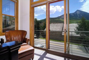 Ein Zimmer mit einer großen SchiebeglasTür, die auf einen Balkon mit Blick auf einen Berg und einen Fluss führt.