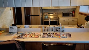 A kitchen with white cabinets, stainless steel appliances, and a counter displaying a Wi-Fi sign and a 'Lodge' sign. - Holiday Lodge on Green Bay (Sturgeon Bay)