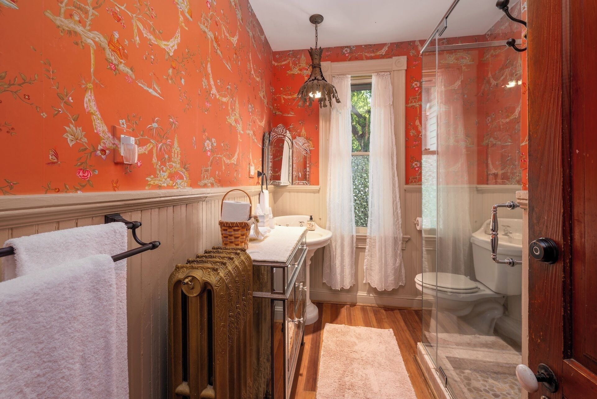 A bathroom with a vintage design, featuring a radiator, a sink, and a toilet.