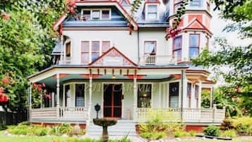 Stunning Victorian-style house with a wrap-around porch and a central entrance flanked by windows.