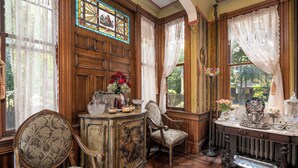 A room with a wooden cabinet, two upholstered chairs, a radiator, and a stained glass window. - Gillis Grier Bed & Breakfast (Salisbury)