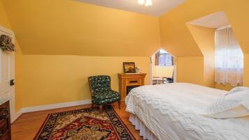 Ein Schlafzimmer mit Bett, Sessel, Kamin und Fenster.