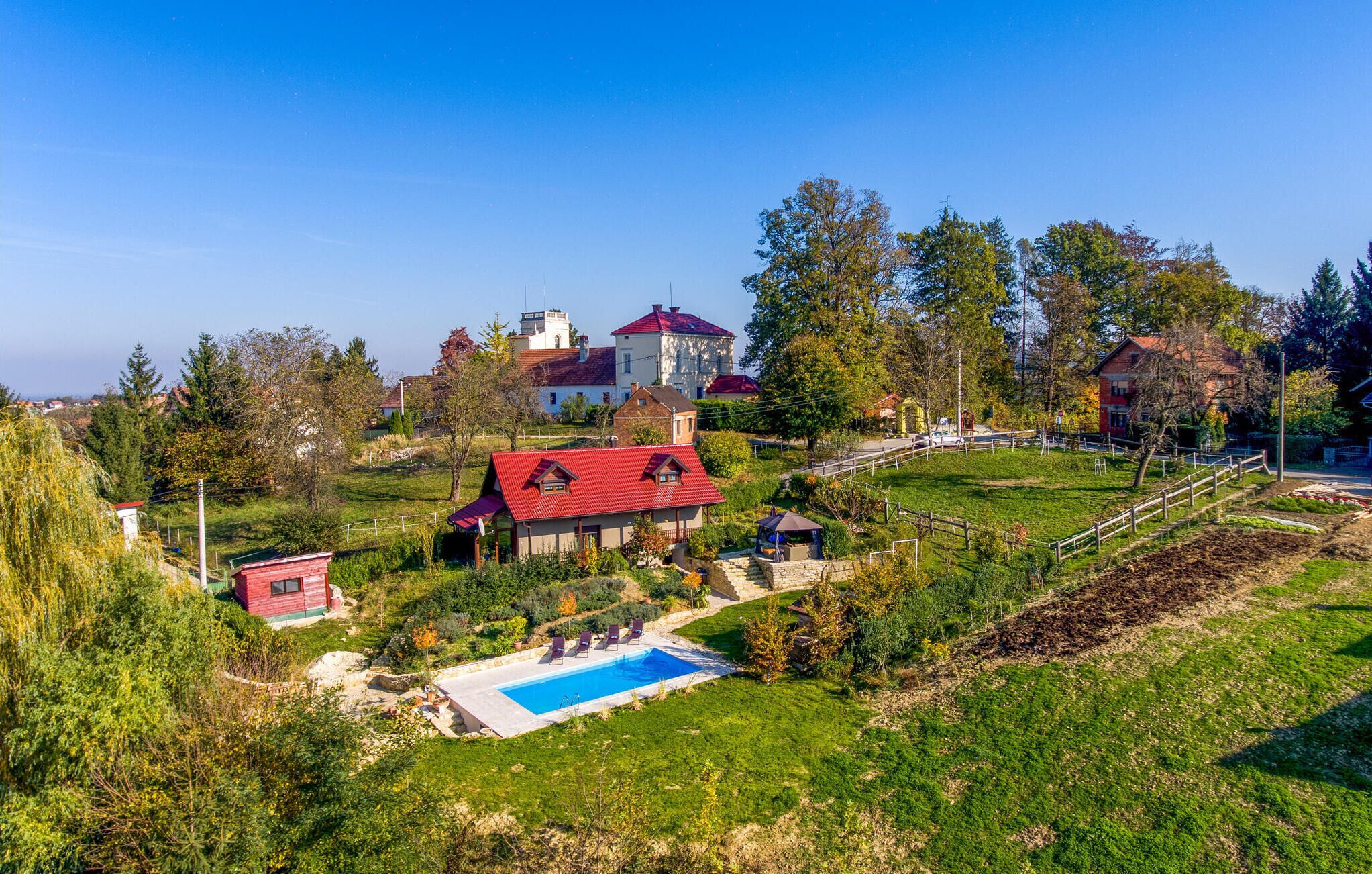 A residential area with a swimming pool, houses, and a small building with a red roof.
