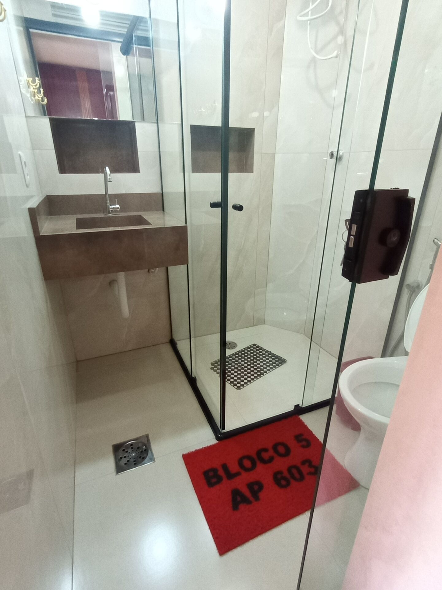 A bathroom with a glass-enclosed shower, a sink, and a toilet.