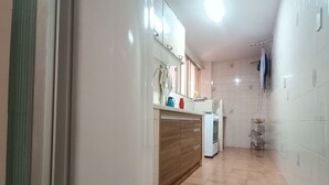 Una cocina con refrigerador, armarios de madera y piso de baldosas.