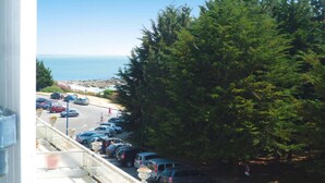 A parking area with cars, a pedestrian path, and a view of the sea. - Apartment in Fouesnant by Sandy Cove (Beg Meil)