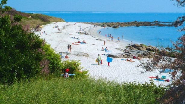 A beach with people sunbathing and swimming, surrounded by greenery and rocks. - Apartment in Fouesnant by Sandy Cove (Beg Meil)