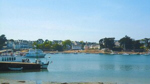 A harbor with boats docked, a pier, and buildings in the background. - Apartment in Fouesnant by Sandy Cove (Beg Meil)