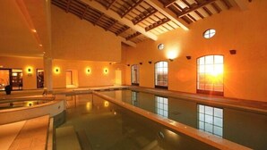 Ein Innenpool mit hoher Decke und großen Fenstern.