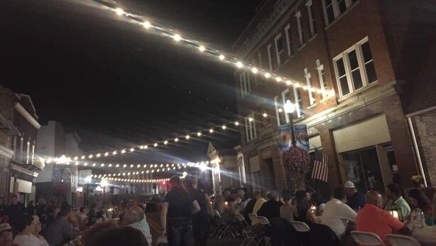 An outdoor seating area with string lights, brick buildings, and a crowd of people. - Gray's Landing- NEWLY Renovated / 1.8 miles to the ARK! (Williamstown)