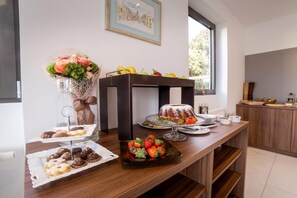 A buffet table with various food items, a decorative vase, and a window view.