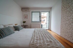 A bedroom with a bed, a radiator, a window with blinds, and a patterned wall.