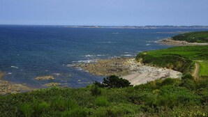 Un paisaje costero con costa rocosa, un sendero cubierto de hierba y una vista despejada del mar.