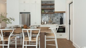 Una cocina moderna con armarios blancos, una mesa de comedor de madera y un horno empotrado.