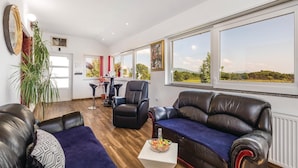 A spacious living room with leather sofas, a coffee table, and large windows offering a view of the countryside. - Stunning home in Gospic with sauna (Gospic)