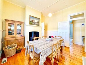 A dining area with a table, chairs, a cabinet, and a fireplace.