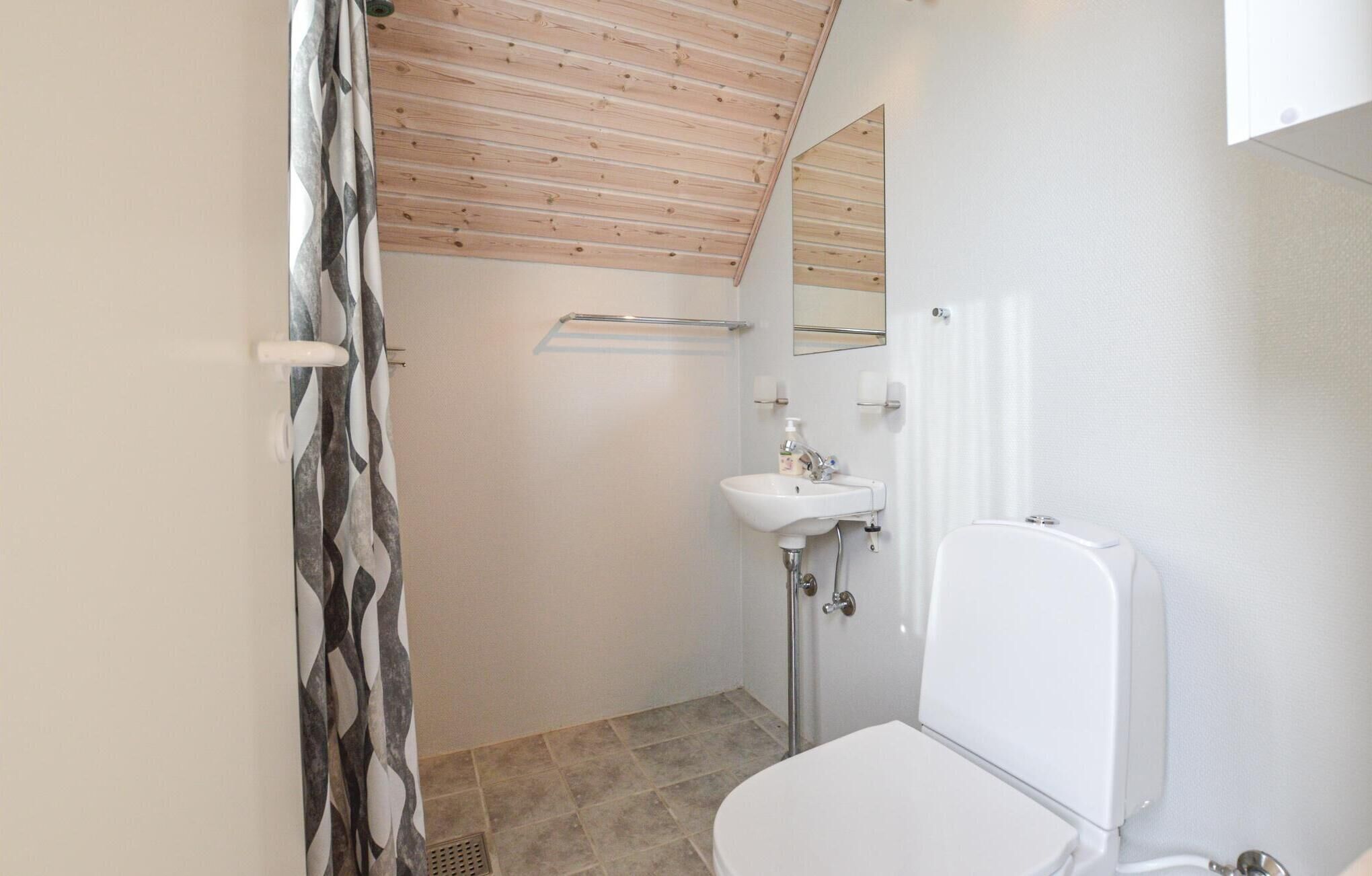 Un bagno piccolo con il water bianco, un lavandino e una tenda della doccia.