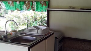 A compact kitchen with a sink, a small stove, and a trash bin. - Pension Chez Glorine (Rangiroa)