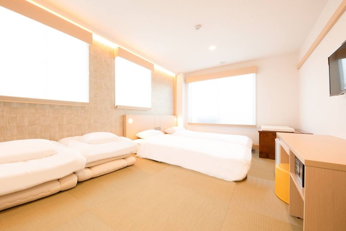 A hotel room with two beds, a small desk, and a TV.