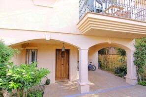 A residential building with a wooden door, a balcony, and a bicycle parked outside.