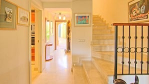 A hallway with a staircase, framed artwork on the walls, and a door leading to another room. - Mijas Costa Lovely Holiday Home for 6 (Mijas Costa)