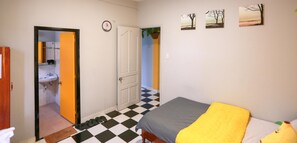 Una habitaci ón con cama, un baño con lavabo y una puerta que da a otra habitación.