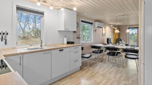 A modern kitchen with a large island, white cabinetry, and a dining area with black chairs.