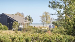 A coastal property with a large building, a view of the sea, and a parking area.