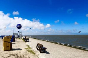 A beach with a sign reading "NIVE," a bench, and a lifeguard tower. - Bungalow, Dornumersiel (Dornumersiel)