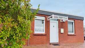 A red brick building with a white door, windows, and a small porch.