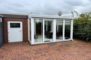 A modern house with a glass extension, a brick exterior, and a satellite dish. - Bungalow, Dornumersiel (Dornumersiel)