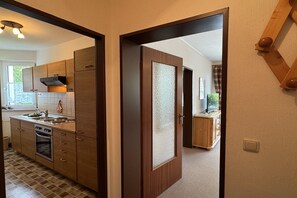 A modern kitchen with wooden cabinets, a built-in oven, and a window with a view.