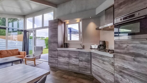Cozinha moderna com uma janela ampla, área de refeições com mesa e cadeiras, e vista para o exterior.