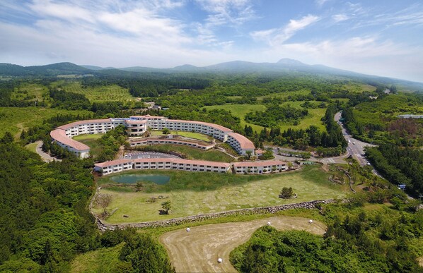 An aerial view of a large, circular hotel with multiple floors and a central courtyard. - Club ES Jeju Resort (Seogwipo)