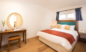A bedroom with a bed, a wooden desk, a mirror, and a nightstand. - Club ES Jeju Resort (Seogwipo)