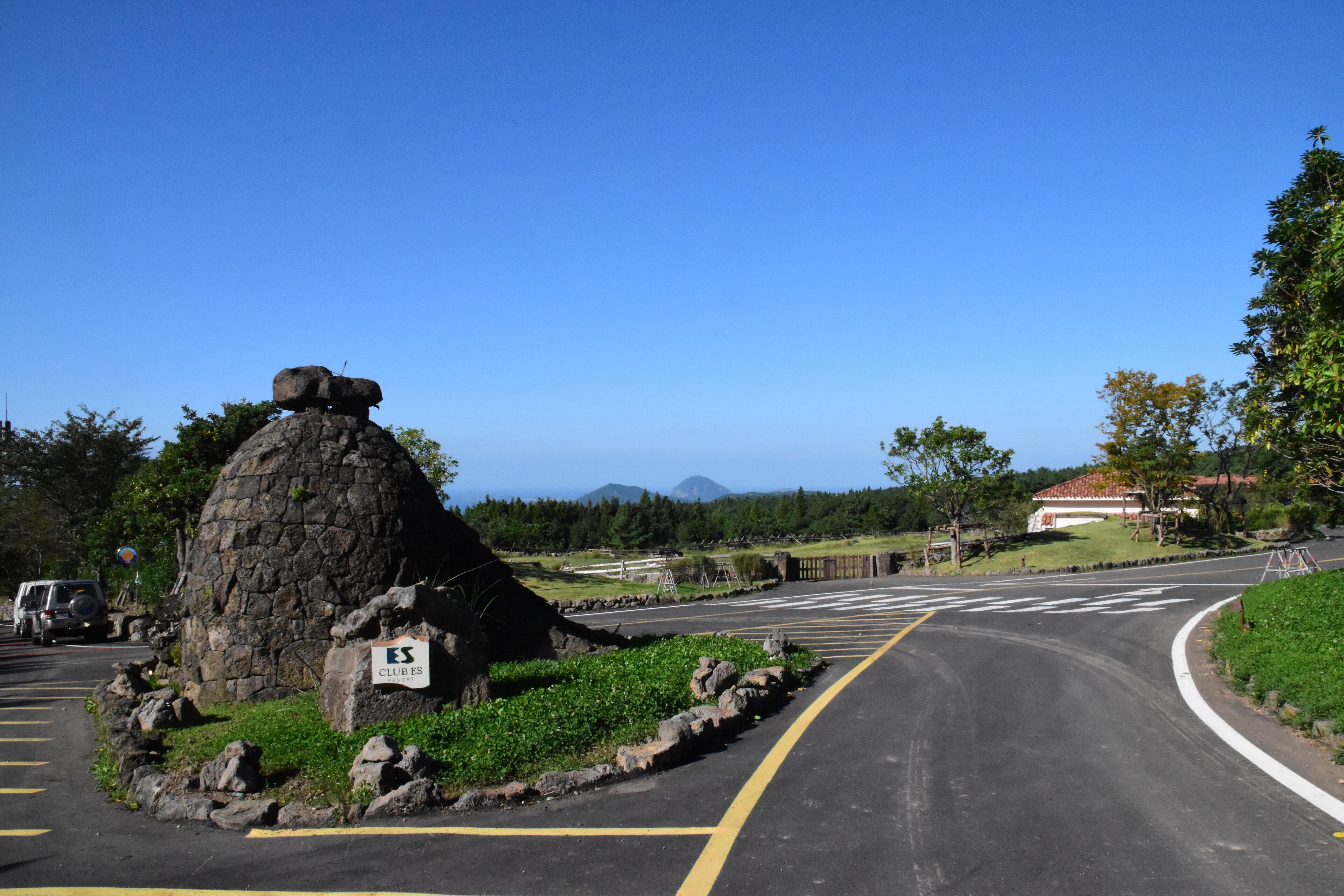 A road with a stone monument and a sign labeled 'ES CLUBES'.