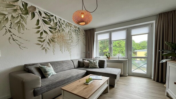 A modern living room with a sectional sofa, a wooden coffee table, and a large window with curtains.
