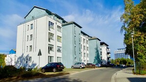 A multi-story residential building with a modern design, featuring balconies and a flat roof.