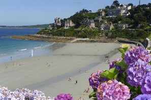 Une plage avec des gens, un ciel dégagé et des maisons en arrière-plan.