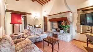 A cozy living room with a fireplace, floral sofa, and a wooden table.