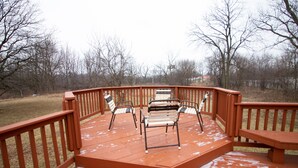 Une terrasse en bois avec deux chaises et un banc, entourée d’une balustrade en bois.