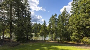 Una terraza de madera con vistas a un lago y un bosque denso.