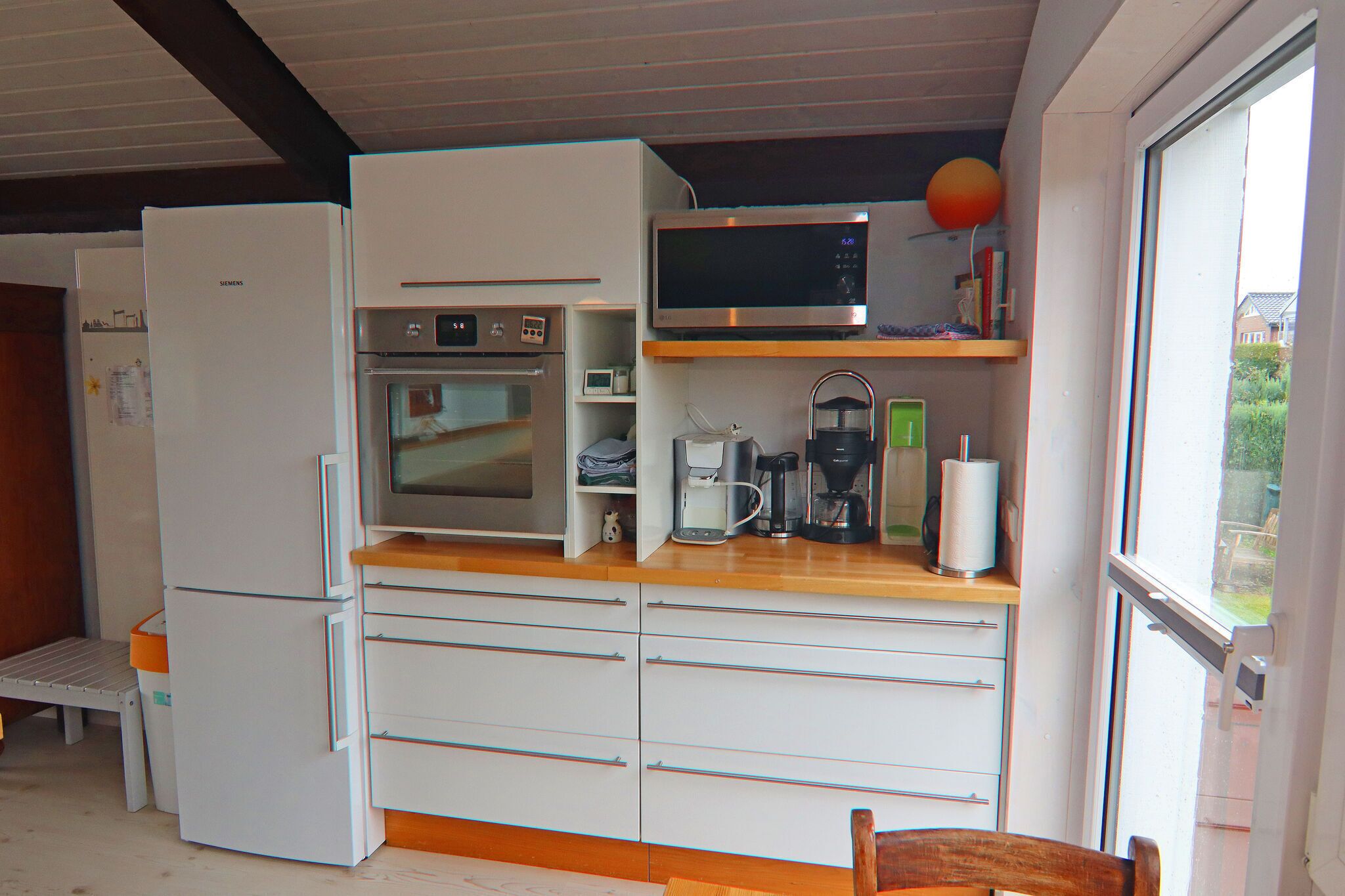 Een kleine keuken met een koelkast, magnetron, oven en koffiezetapparaat.