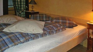 A bed with plaid bedding, a bedside lamp, and a nightstand.