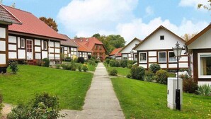 A row of traditional half-timbered houses with a central pathway leading to a distant building.