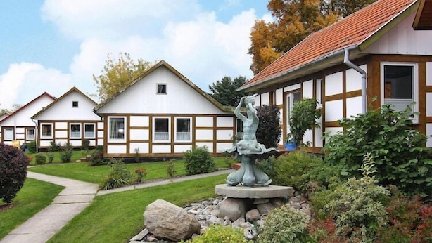 A row of traditional half-timbered houses with a stone fountain in the garden.